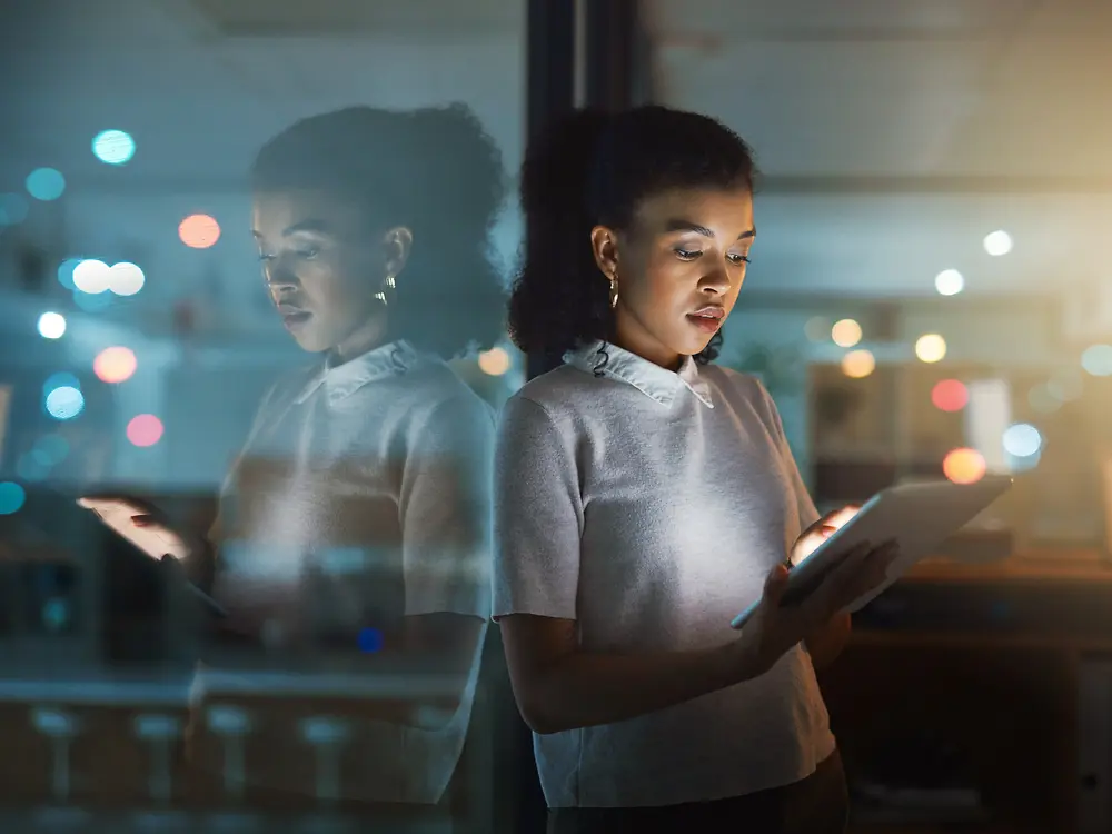 Een vrouw typt op een tablet, met een geconcentreerde, gefocuste blik.