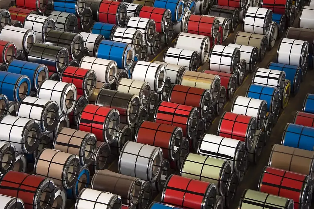 Detailopname van opgestapelde metalen rollen in een industrieel magazijn.