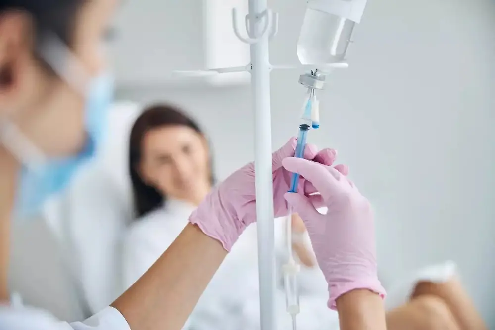Medisch personeel met een infuuszak in een zorgomgeving.