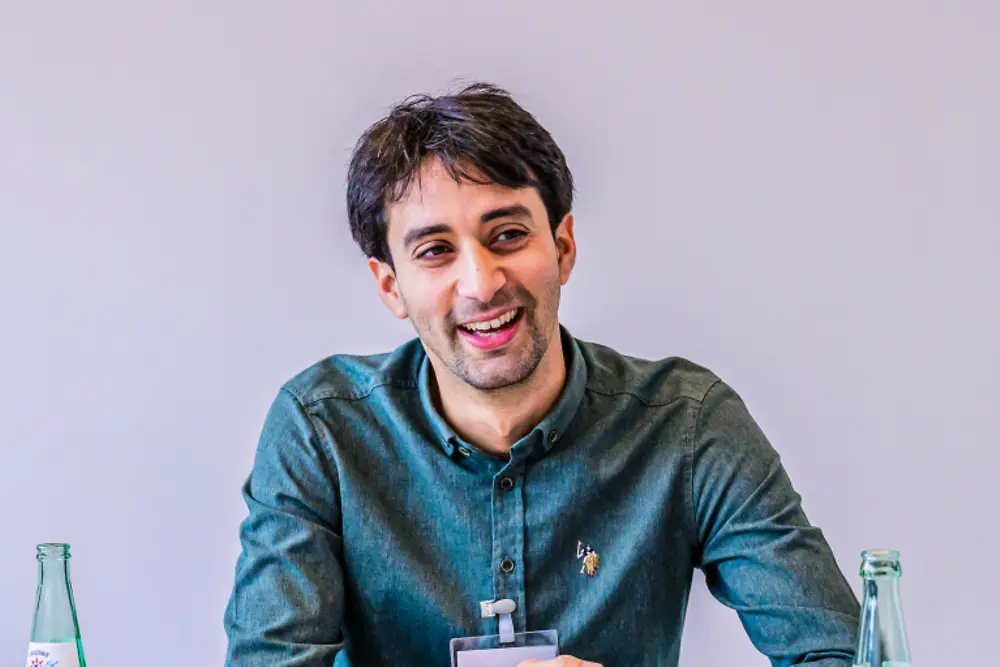 Senior leidinggevende in een professionele vergaderomgeving, gezeten aan een tafel met documenten tijdens een strategiesessie bij Henkel.