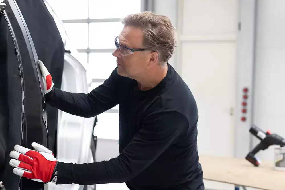 Een monteur die een autodeur repareert of onderhoudt in een autowerkplaats.
