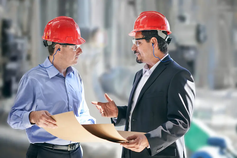 Ingenieurs met rode helmen op een productiesite.