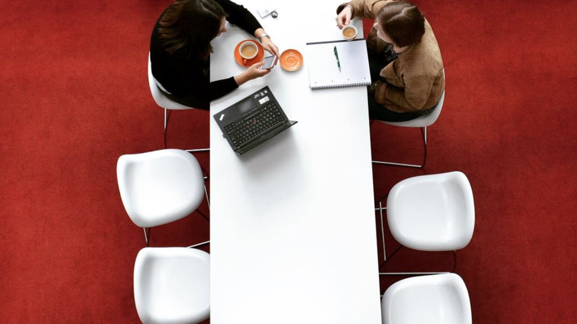 Foto van bovenaf met 2 Henkel-medewerkers die aan een witte tafel zitten