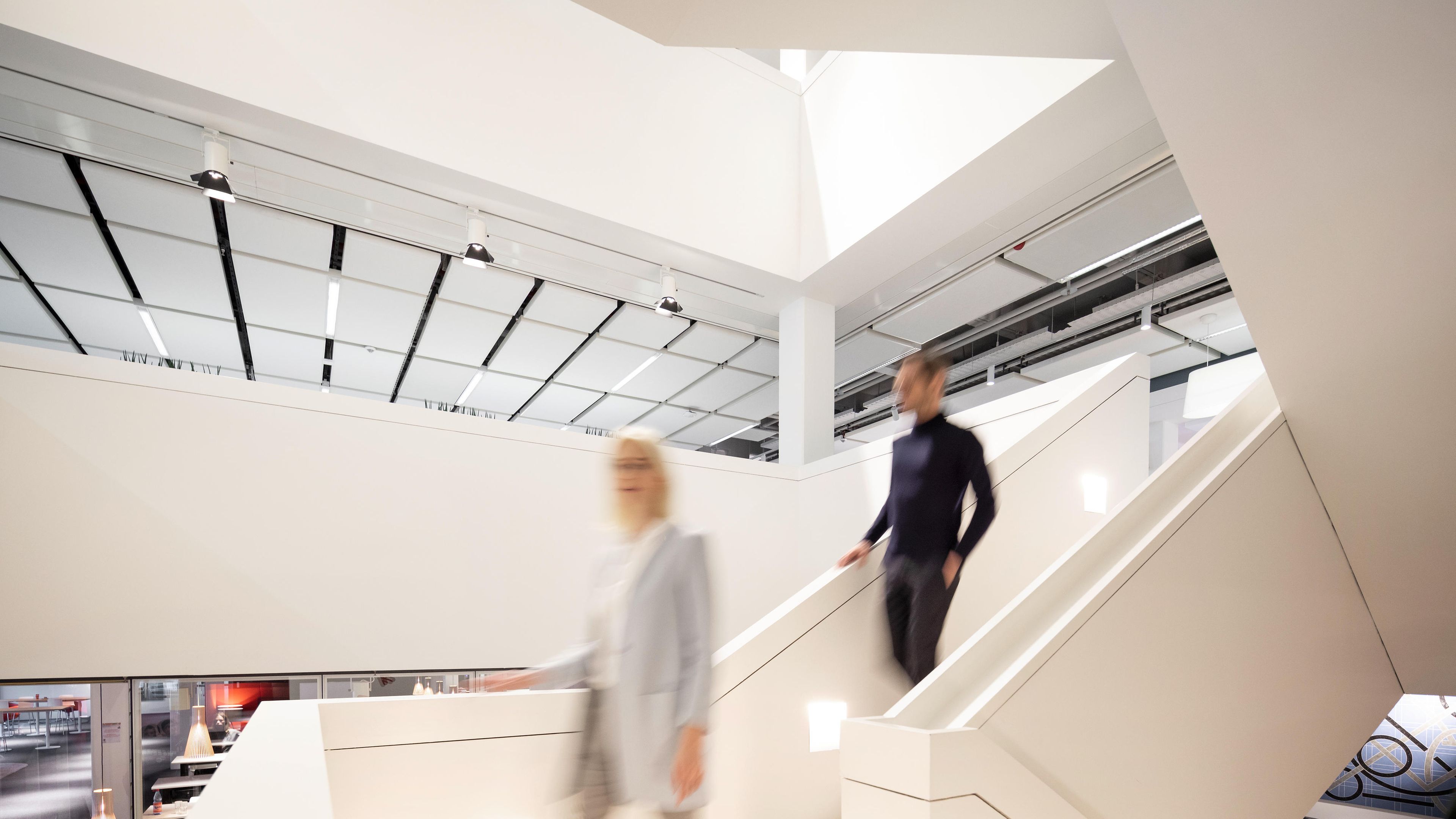 2 Henkel-medewerkers lopen witte trappen af in een kantoorruimte